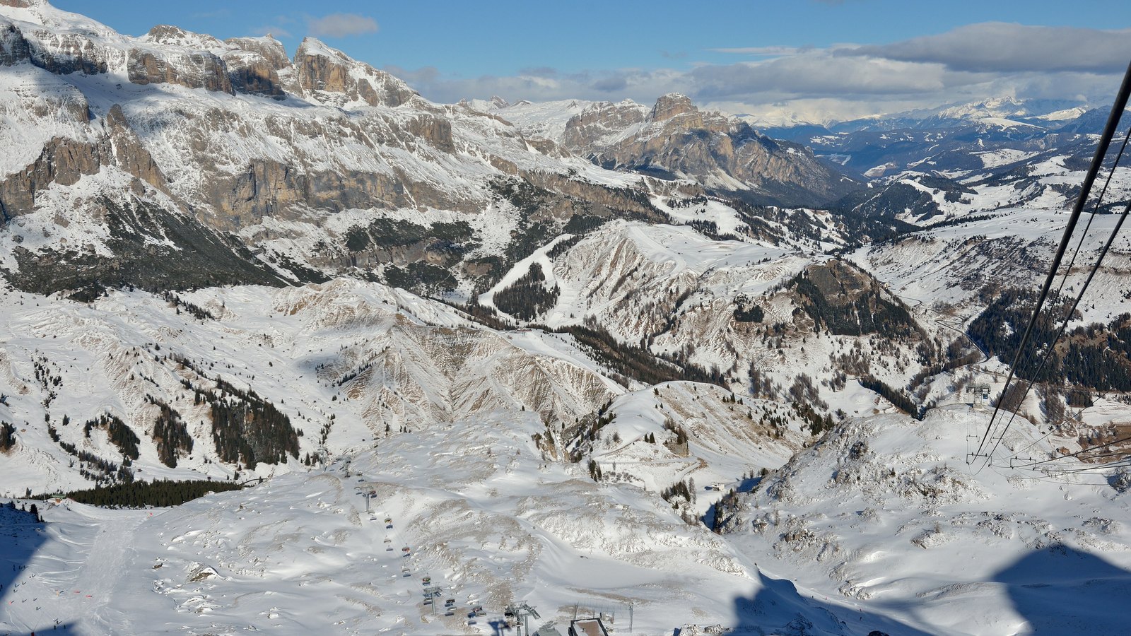 Blick von Porta Vescovo auf die Sellagruppe, Alta Badia und das Passo Campolongo, im Vordergrund Skilifte und verschneite Hänge